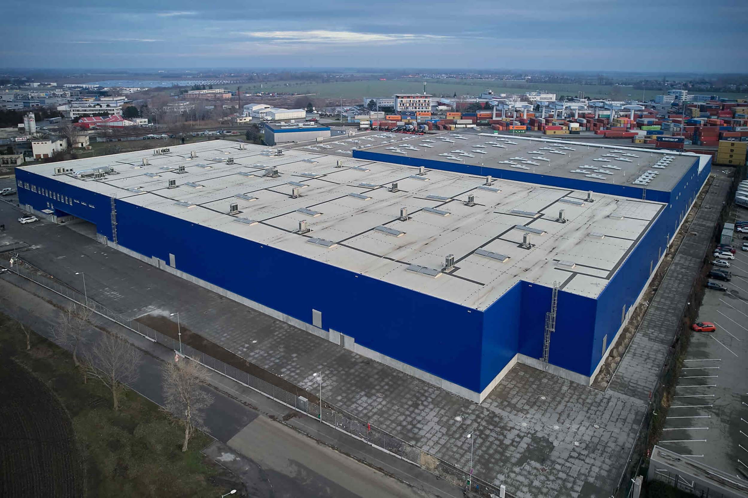 Aerial view of a large blue warehouse in an industrial area