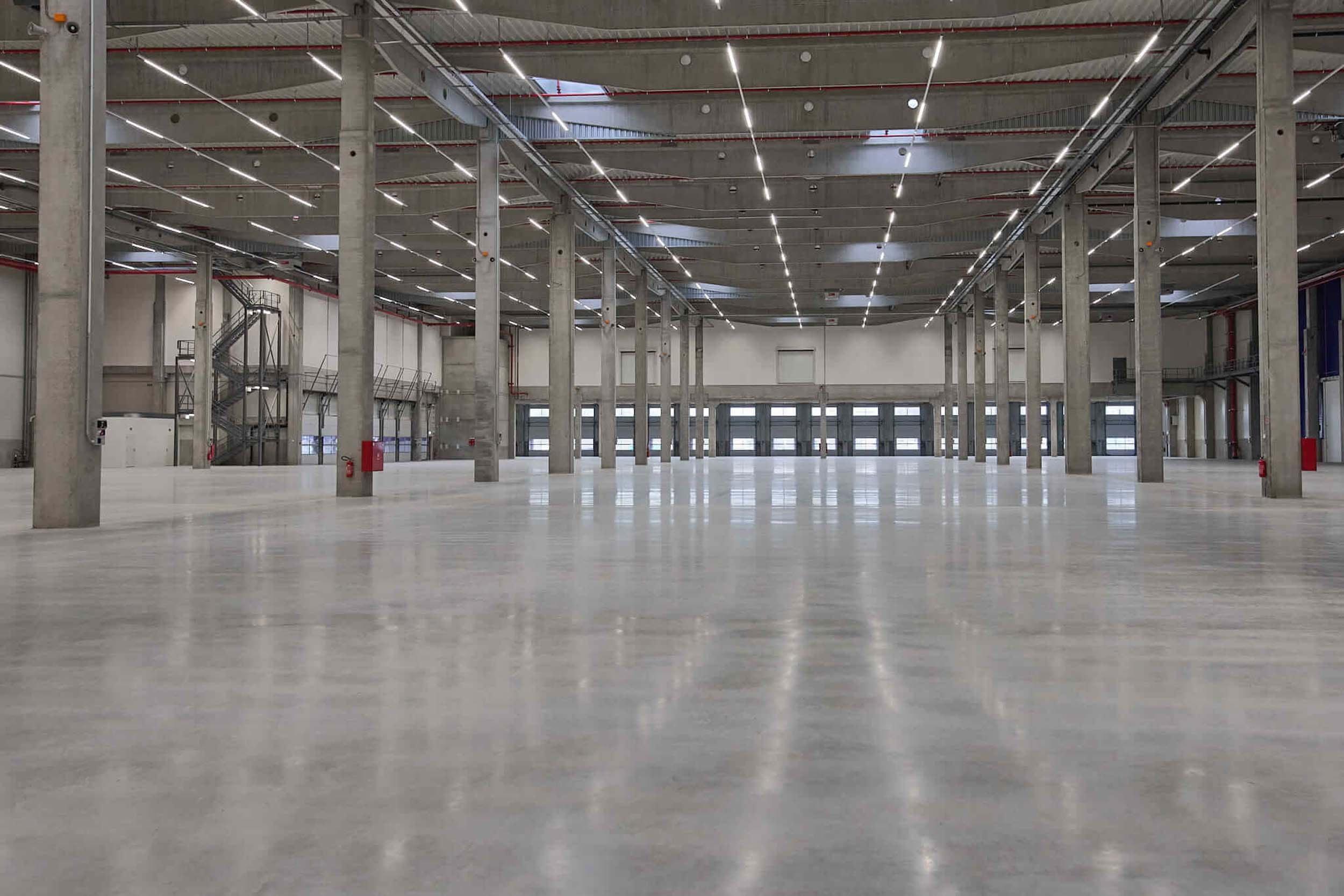 Interior view of a spacious, modern industrial hall with a polished concrete floor and lighting